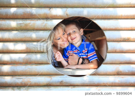 Mother and son peeks through hole at playground 9899604