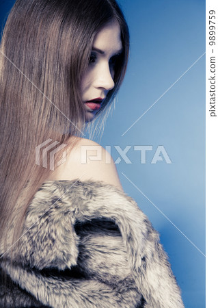 Portrait of girl with long hair. Young woman in fur coat on blue. Portrait of girl with long hair. Young woman in fur coat on blue. 9899759