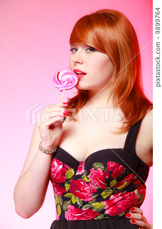 Sexy young woman holding candy. Redhair girl eating sweet lollipop 9899764