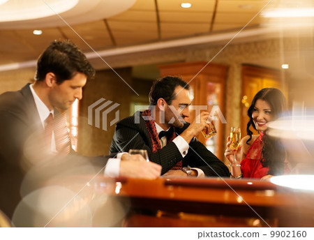 Happy young people behind gambling table with drinks 9902160