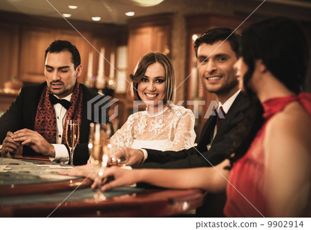 Group of happy young people behind gambling table with drinks 9902914