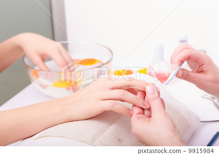 Beautician with file filing nails female client. Woman spa beauty salon 9915984