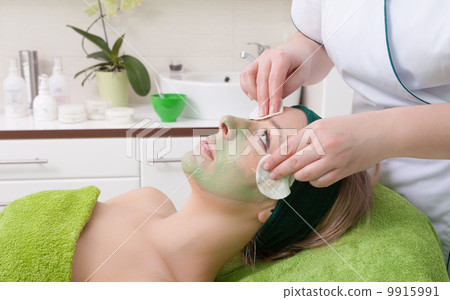Beauty salon. Cosmetician removing facial mask from woman face. 9915991
