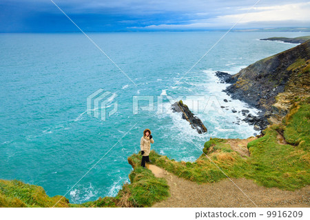 Woman standing on rock cliff by the ocean Co. Cork Ireland Woman standing on rock cliff by the ocean Co. Cork Ireland 9916209