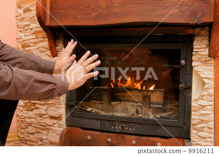 man warming hand at fireplace man warming hand at fireplace 9916211