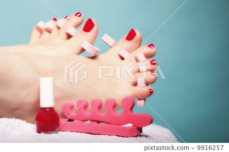 foot pedicure applying red toenails on blue 9916257