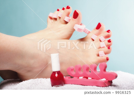 foot pedicure applying red toenails on blue 9916325