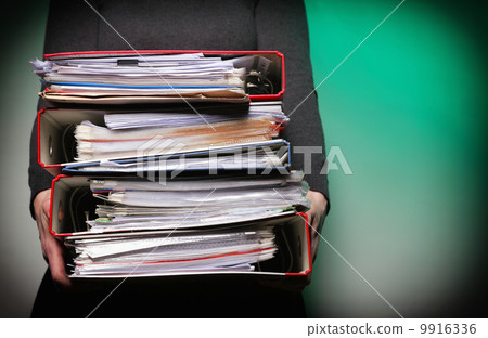 Female office worker carrying a stack of files Female office worker carrying a stack of files 9916336