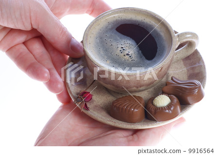chocolate pralines, cup, black coffee and female hand on white 9916564