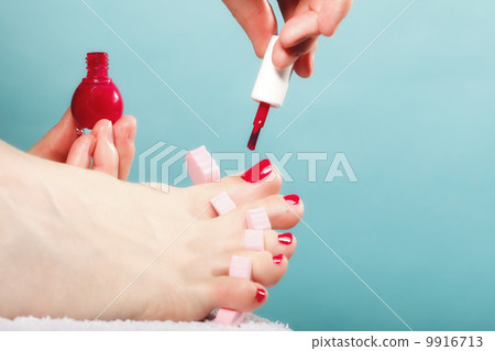 foot pedicure applying red toenails on blue 9916713