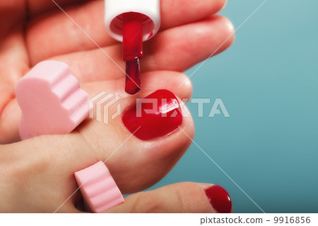 foot pedicure applying red toenails on blue 9916856