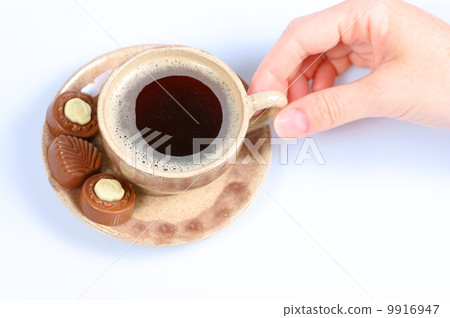 chocolate pralines, cup, black coffee and female hand on white 9916947
