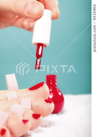 foot pedicure applying red toenails on blue 9916968