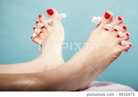 foot pedicure applying red toenails on blue foot pedicure applying red toenails on blue 9916973
