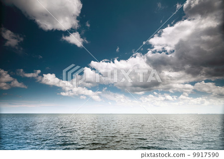 Cloudy blue sky above a surface of the sea Cloudy blue sky above a surface of the sea 9917590
