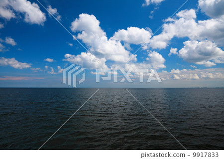 Cloudy blue sky above a surface of the sea Cloudy blue sky above a surface of the sea 9917833