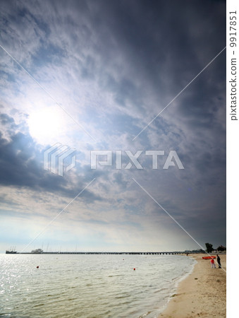 Cloudy blue sky above a surface of the sea 9917851