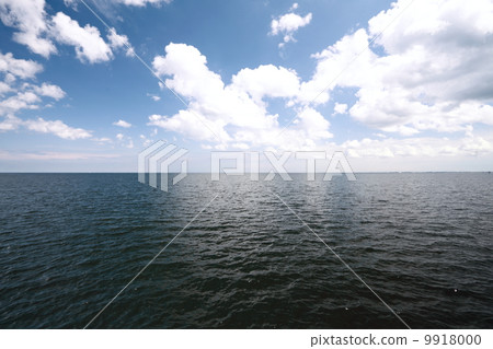 Cloudy blue sky above a surface of the sea 9918000