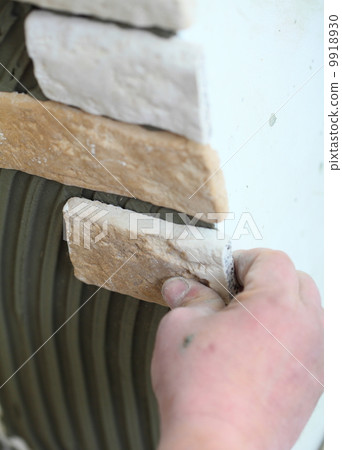 construction worker installing tiles on a wall 9918930