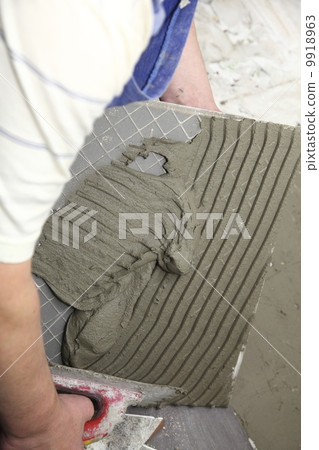 tiler at work bonding of floor tile adhesive 9918963