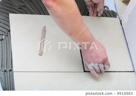 Construction worker is tiling at home, tile floor adhesive Construction worker is tiling at home, tile floor adhesive 9918983