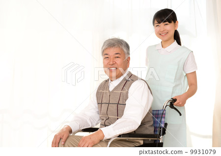 A senior male riding a wheelchair and a helper woman A senior male riding a wheelchair and a helper woman 9931079
