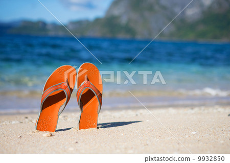 Slippers on sand beach near the water Slippers on sand beach near the water 9932850