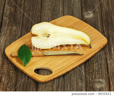 Half of pear and knife on wooden background. 9935831