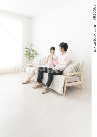 A couple talking while sitting on a sofa and drinking coffee 9936569