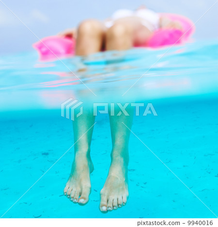 Woman relaxing on inflatable mattress, view from underwater Woman relaxing on inflatable mattress, view from underwater 9940016