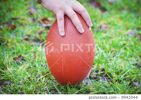Hand on rugby ball on green grass background Hand on rugby ball on green grass background 9942044