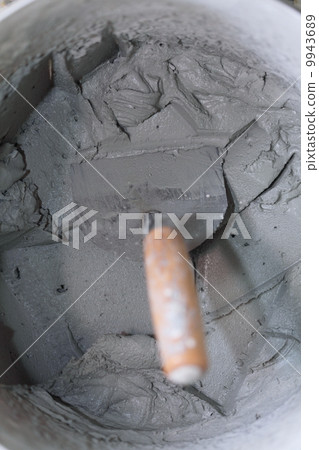 Old dirty trowel and bucket on building site 9943689