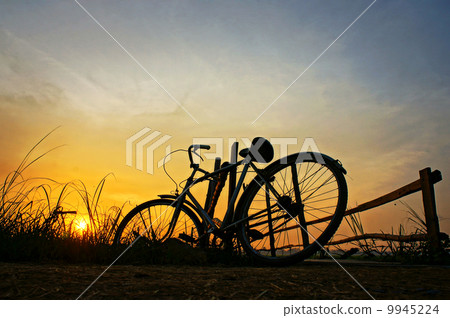 bicycle put up at wooden fence in sunrise bicycle put up at wooden fence in sunrise 9945224