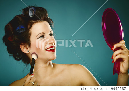 girl in curlers styling hair applying make up 9946587