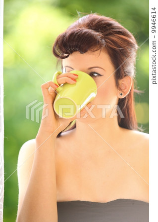 Beautiful Girl Drinking Tea or Coffee Indoor. Green Blurred Background Beautiful Girl Drinking Tea or Coffee Indoor. Green Blurred Background 9946614
