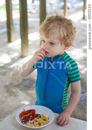Cute little boy eating french fries in summer 9959154
