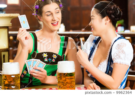 friends drinking beer in Bavarian pub playing cards 9962364