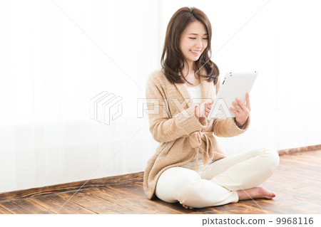 觀看片劑的婦女在窗口邊 觀看片劑的婦女在窗口邊 9968116