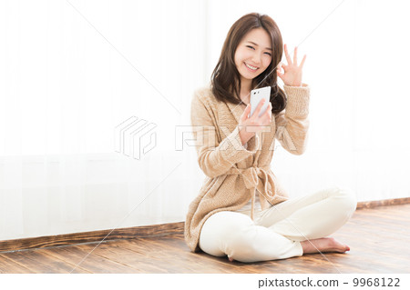 A woman watching a smartphone in a room 9968122