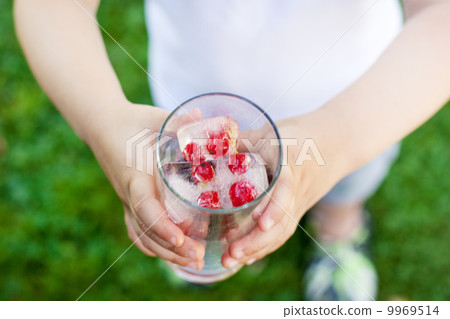 Hands of little child holding a glass with ice cubes Hands of little child holding a glass with ice cubes 9969514