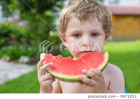 Adorable little toddler boy with blond hairs eating watermelon i Adorable little toddler boy with blond hairs eating watermelon i 9971051