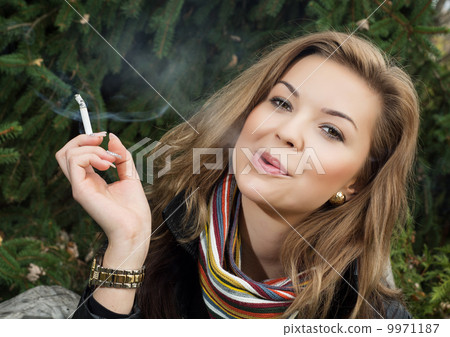 Young caucasian woman smokes a cigarette Young caucasian woman smokes a cigarette 9971187
