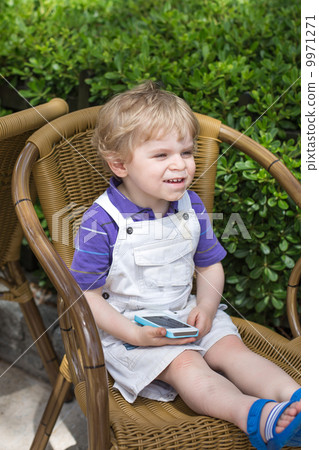 Little blonde toddler boy playing with cell phone 9971271