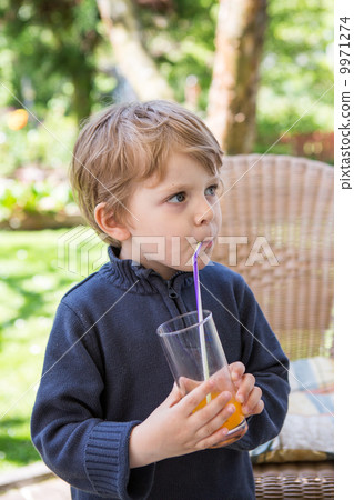 Happy little boy drinking orange juice with straw 9971274