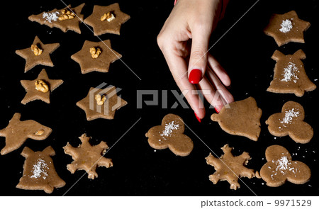 Woman lays gingerbreads on the baking tray by christmas time Woman lays gingerbreads on the baking tray by christmas time 9971529