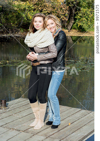 Two beautiful young women and pond in the autumn park Two beautiful young women and pond in the autumn park 9971575