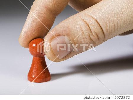 Hand holding red pawn on white background 9972272
