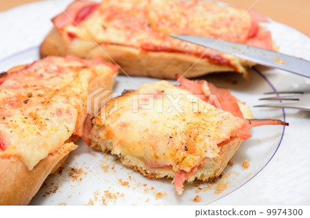 Remains of the ham and cheese baked toast on the plate. Remains of the ham and cheese baked toast on the plate. 9974300