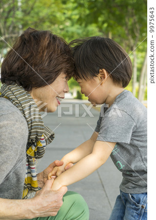Grandmother hugging grandson in a park in an asian city on a sunny day. 9975643