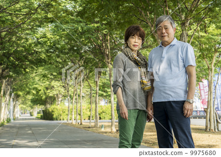 Portrait of an elderly couple traveller taking photos in a park with in an asian city on a sunny day 9975680